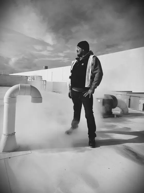 Wetzel Welding technician walking a commercial rooftop past custom stainless steel process piping