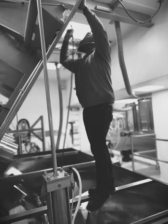 Wetzel Welding welder installing stainless steel piping above a process tank inside a food-grade facility