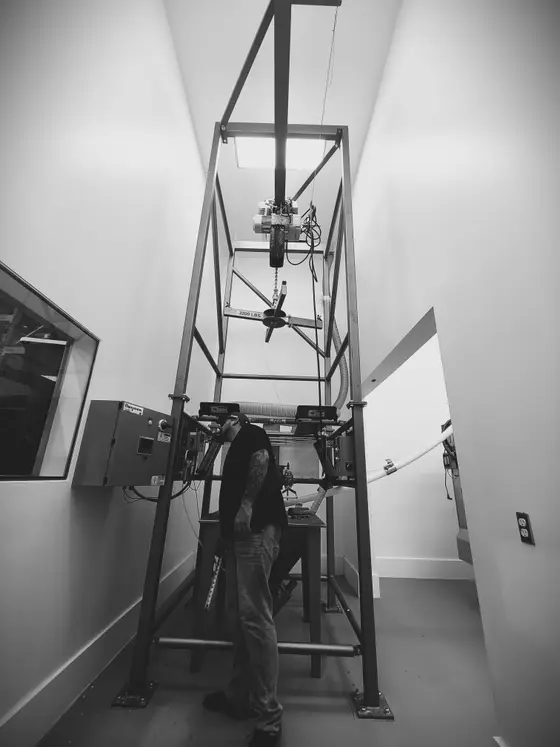 Wetzel Welding technician with a custom fabricated steel test frame in a narrow equipment room